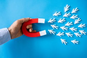 A magnet attracting small white human like figures.